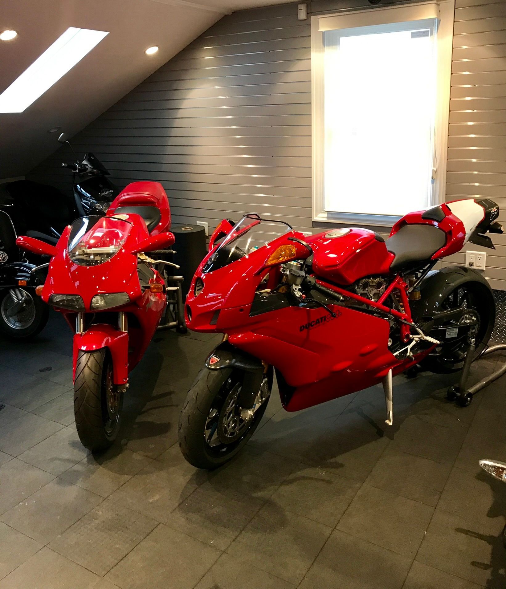 two red Ducati motorcycles are parked in a garage