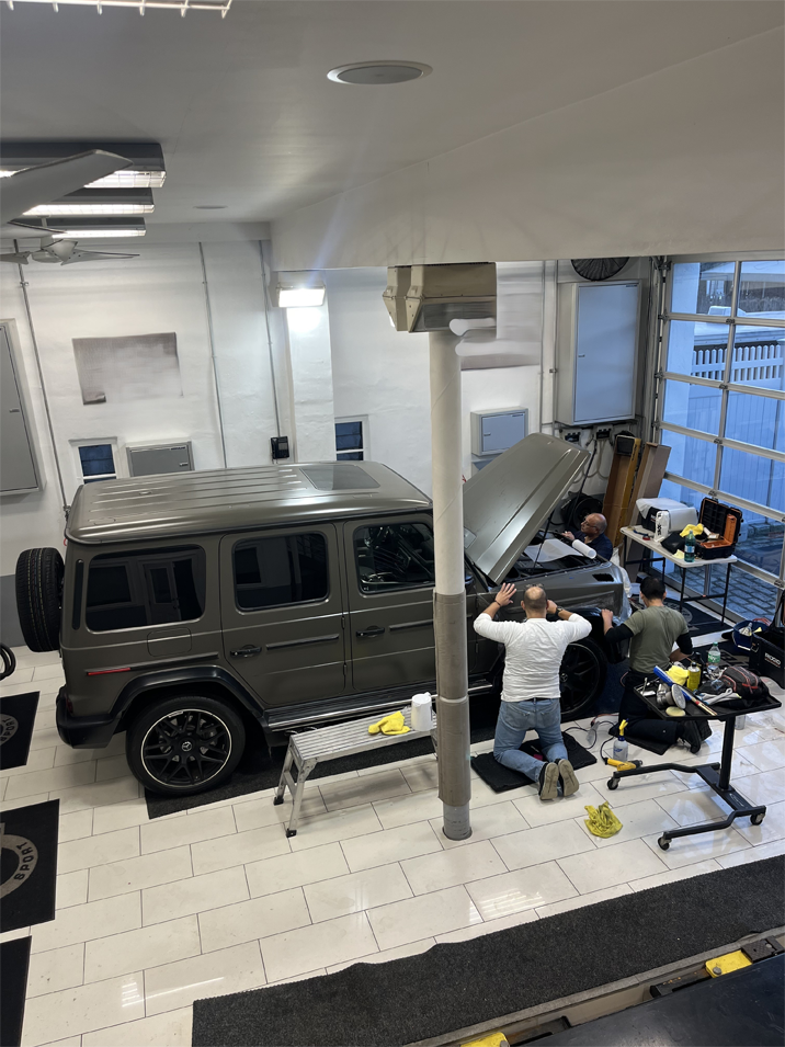 A group of people are working on a car in a garage.