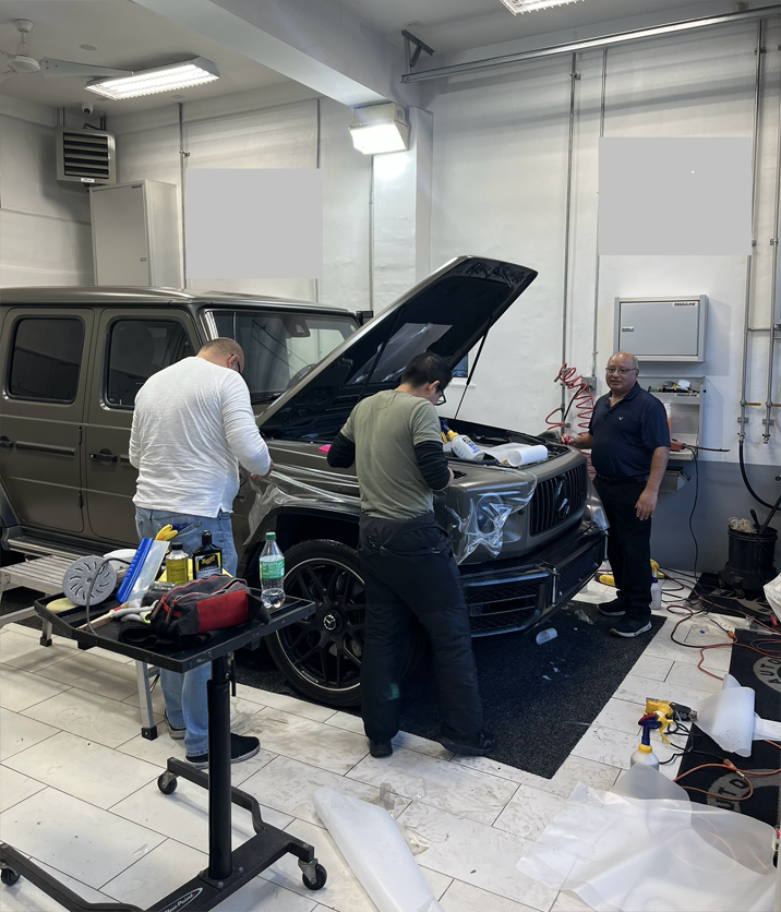 A group of men are working on a car in a garage.