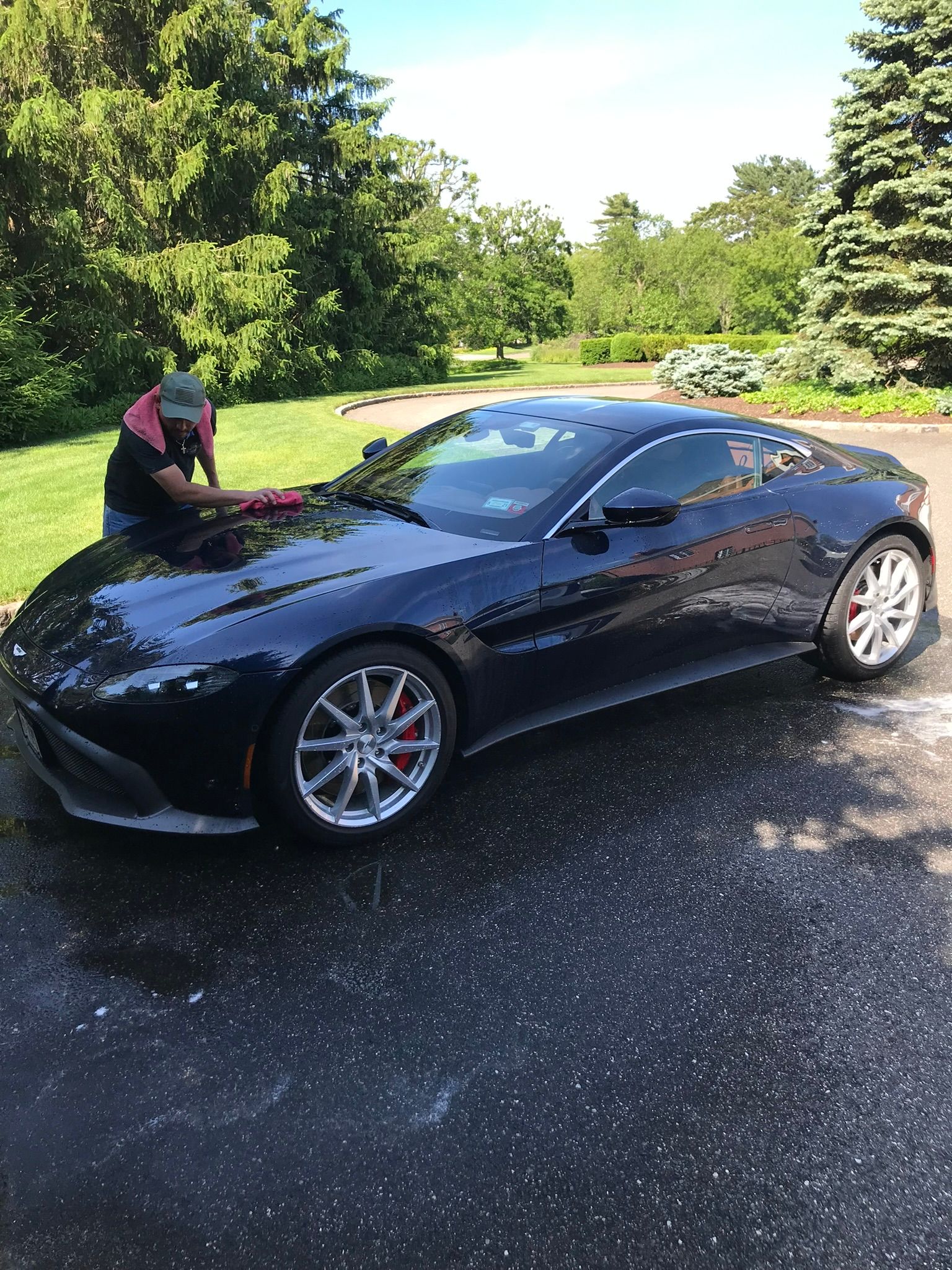 man cleaning black car on a driveway