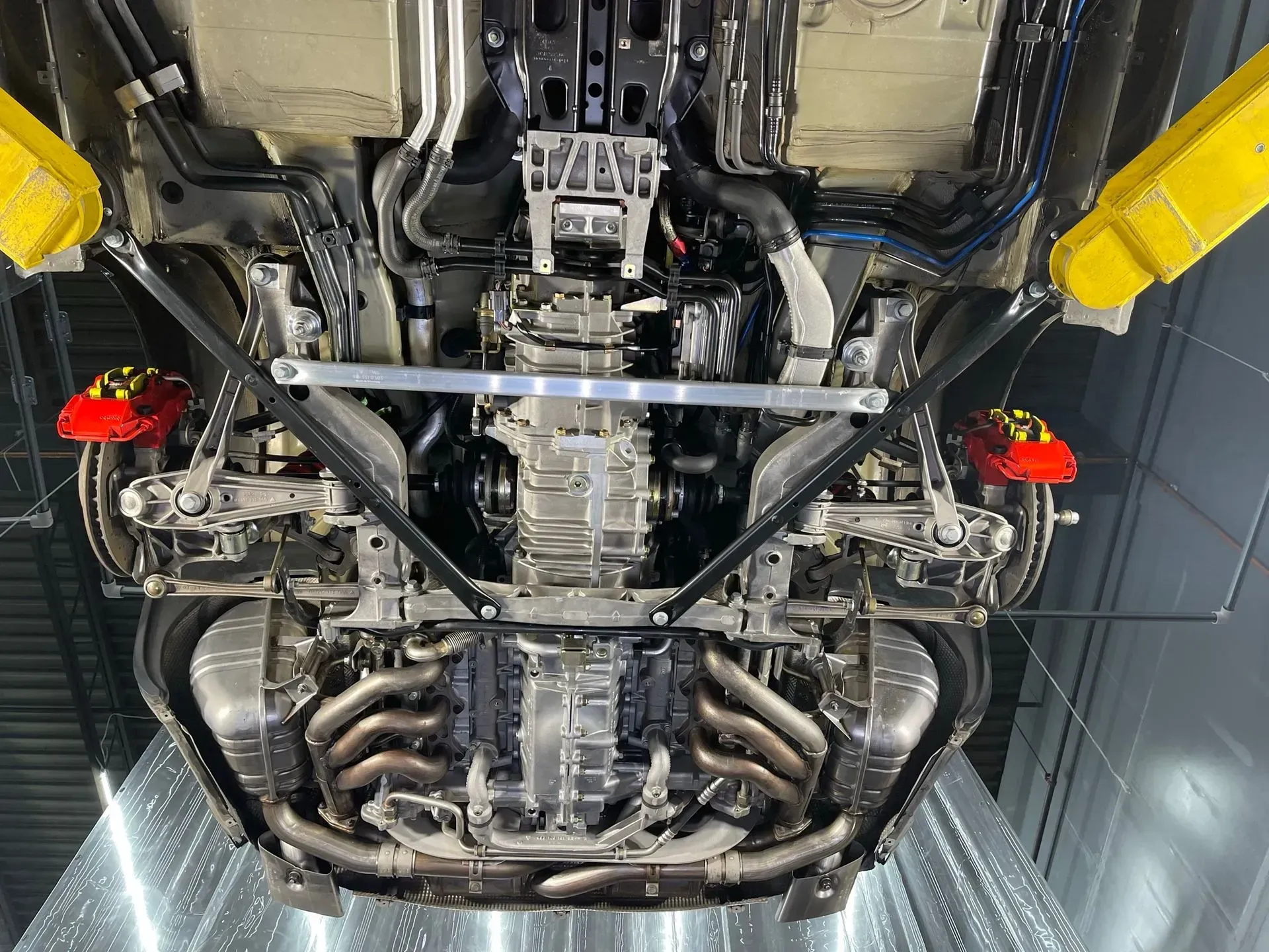 A close up of the underside of a car with a yellow lift.