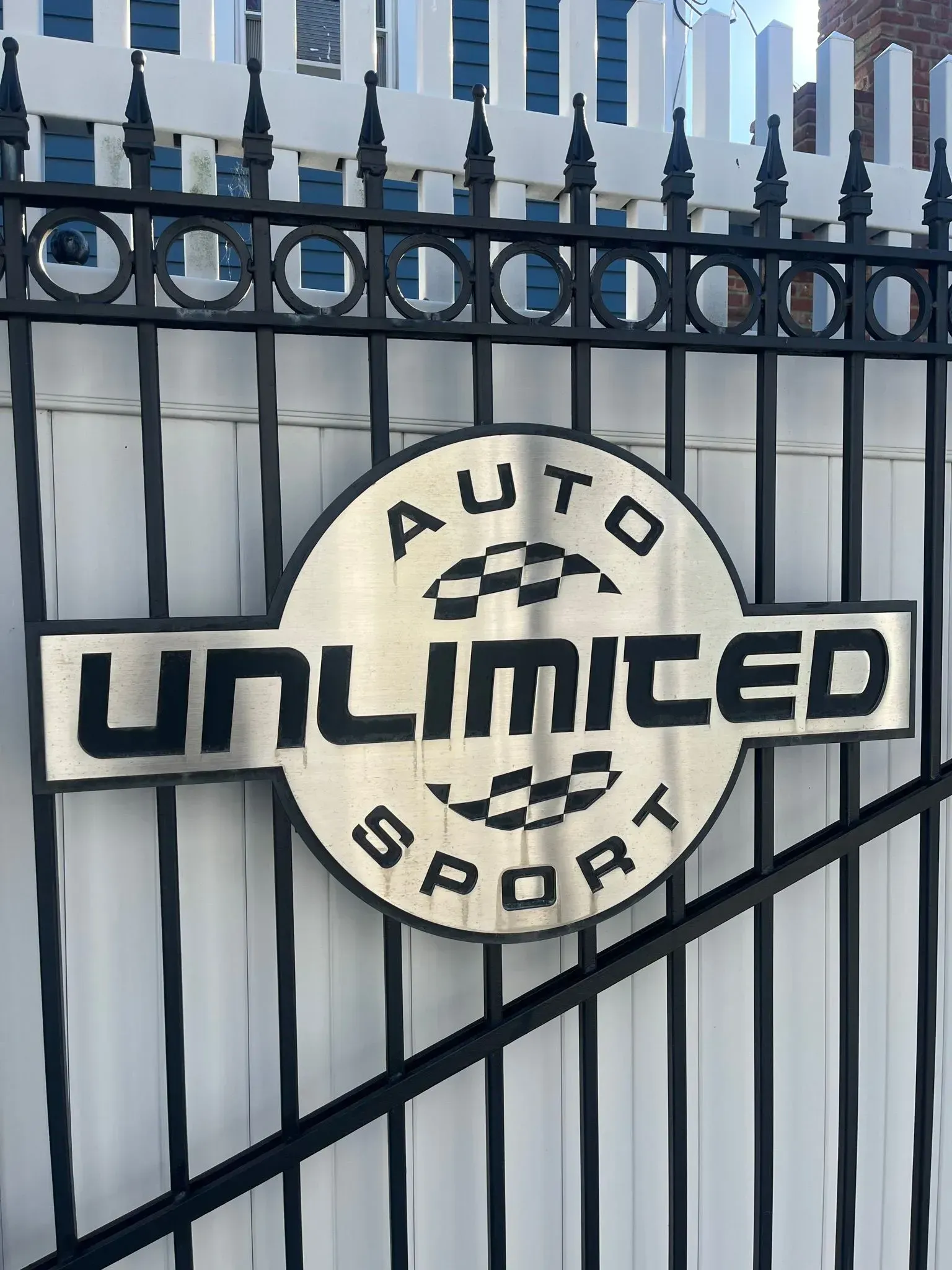 A sign on a fence that says auto unlimited sport.