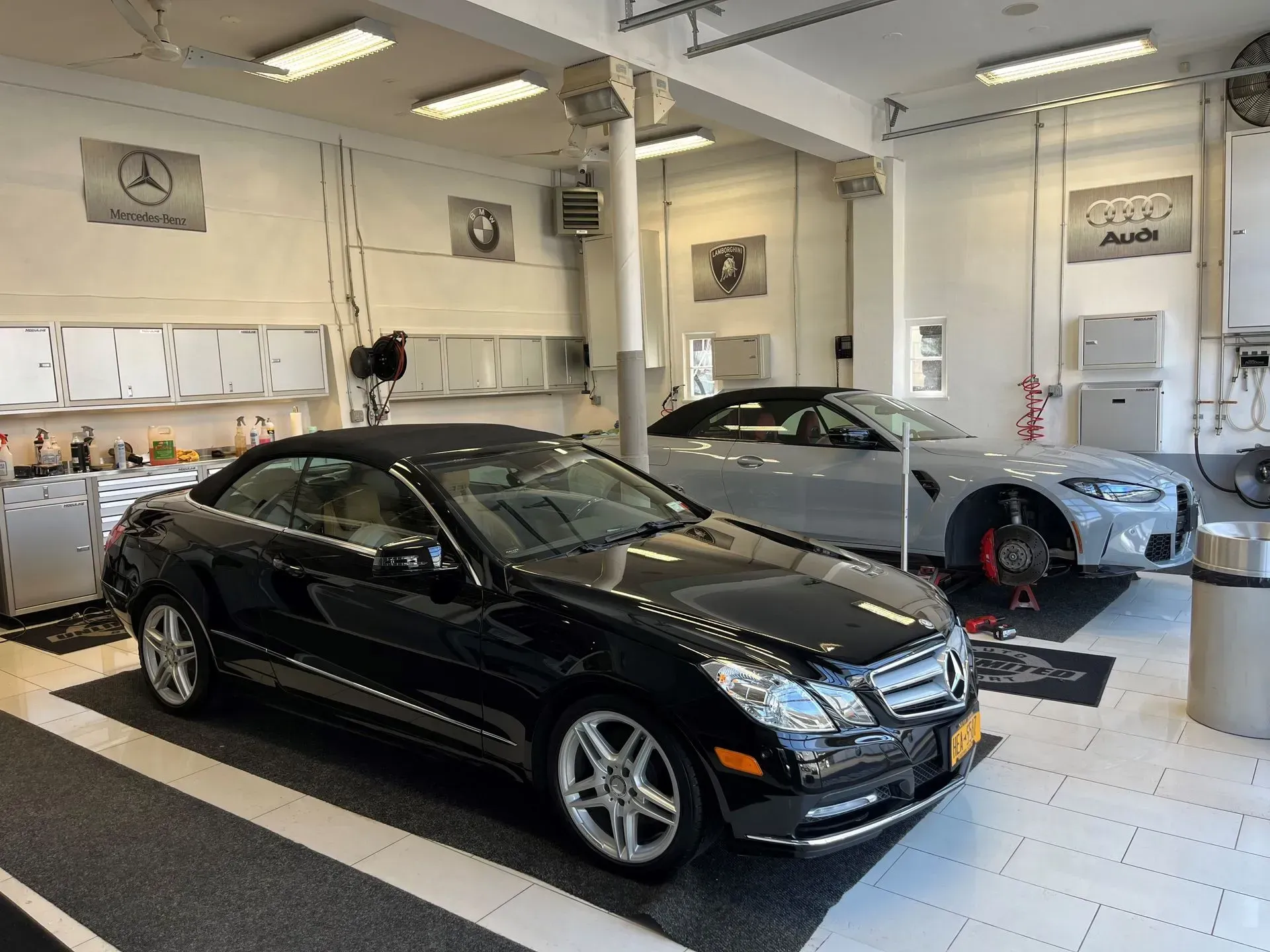 A black car is parked in a garage next to a silver car.