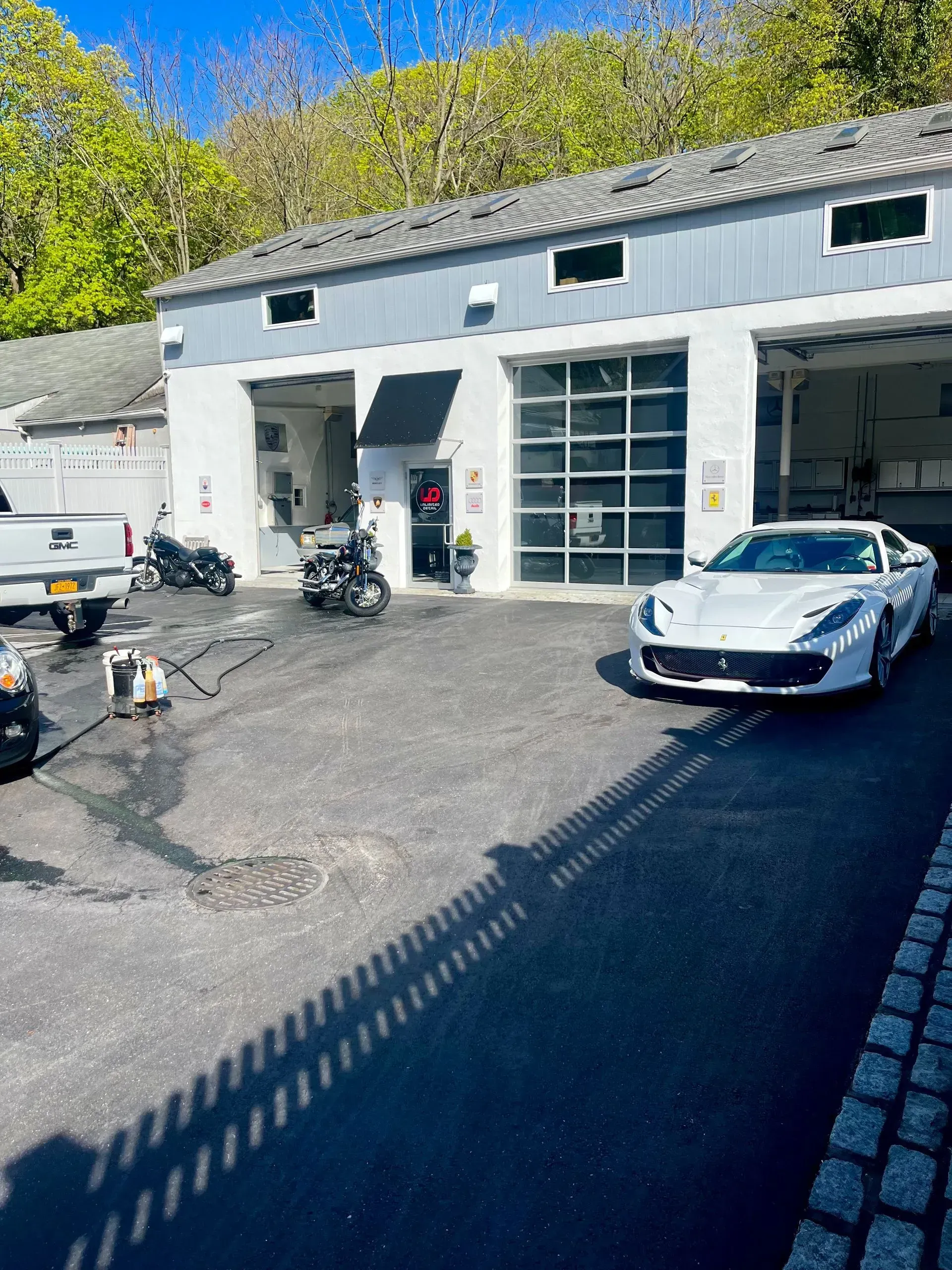 A white sports car is parked in front of a garage.