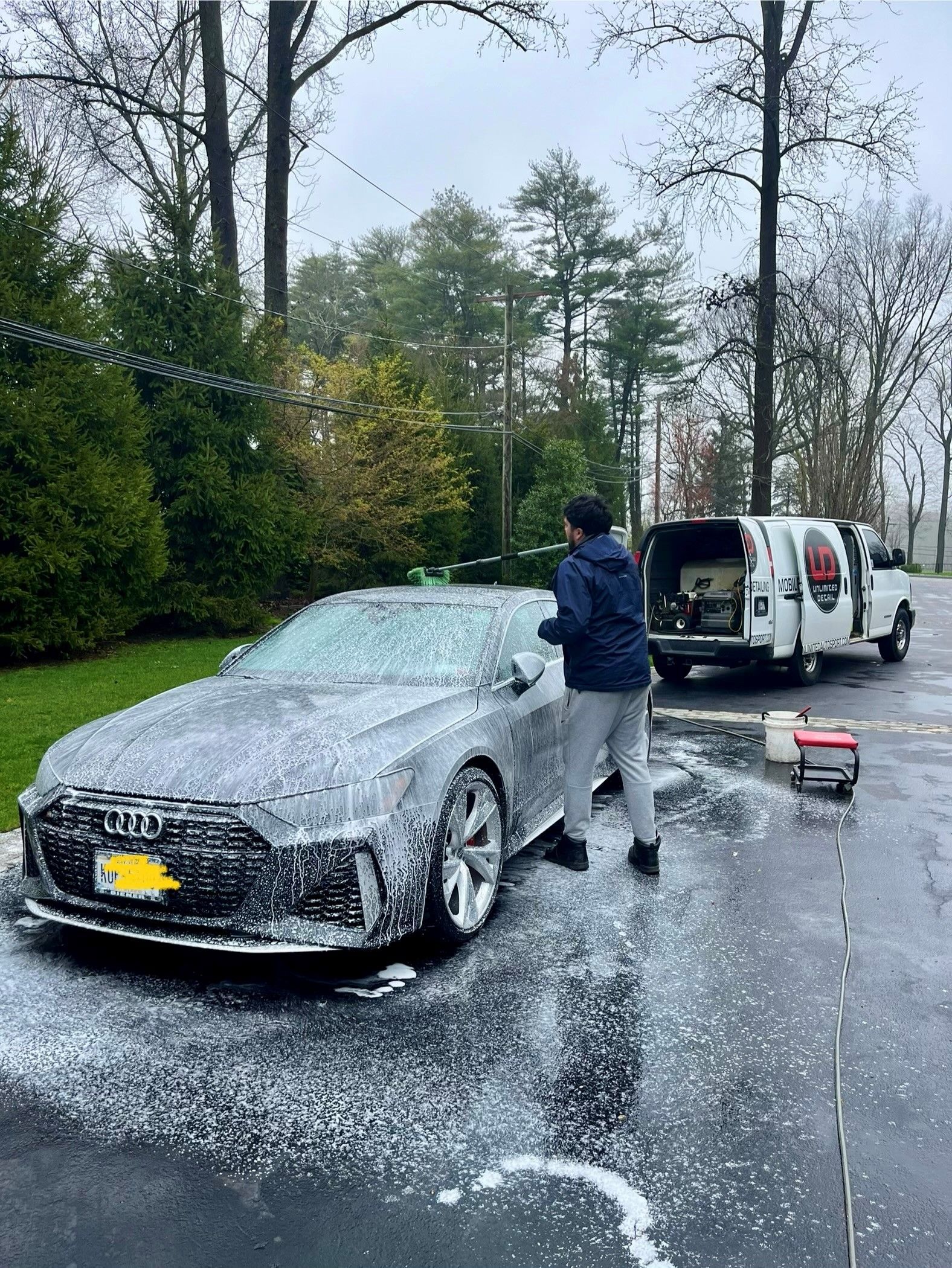 A man is washing a car with foam in a parking lot.