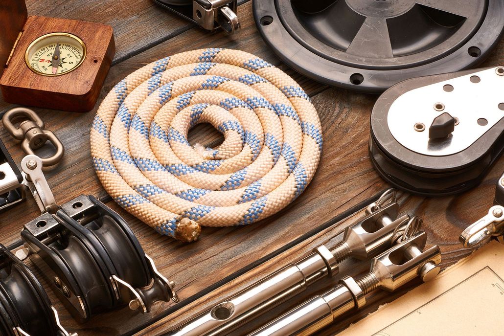Coiled climbing rope and metal nautical gear arranged on a wooden surface