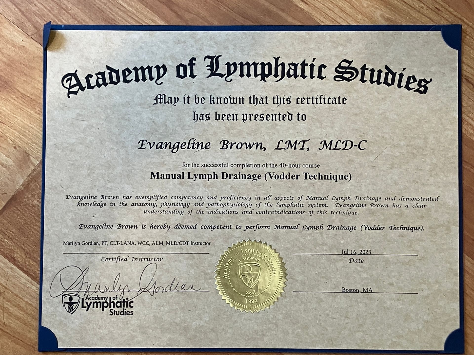 Certificate from the Academy of Lymphatic Studies with gold seal on a wooden background