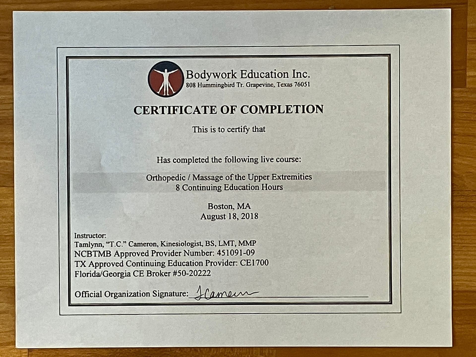 Framed certificate of completion with black text and a circular logo on a light background