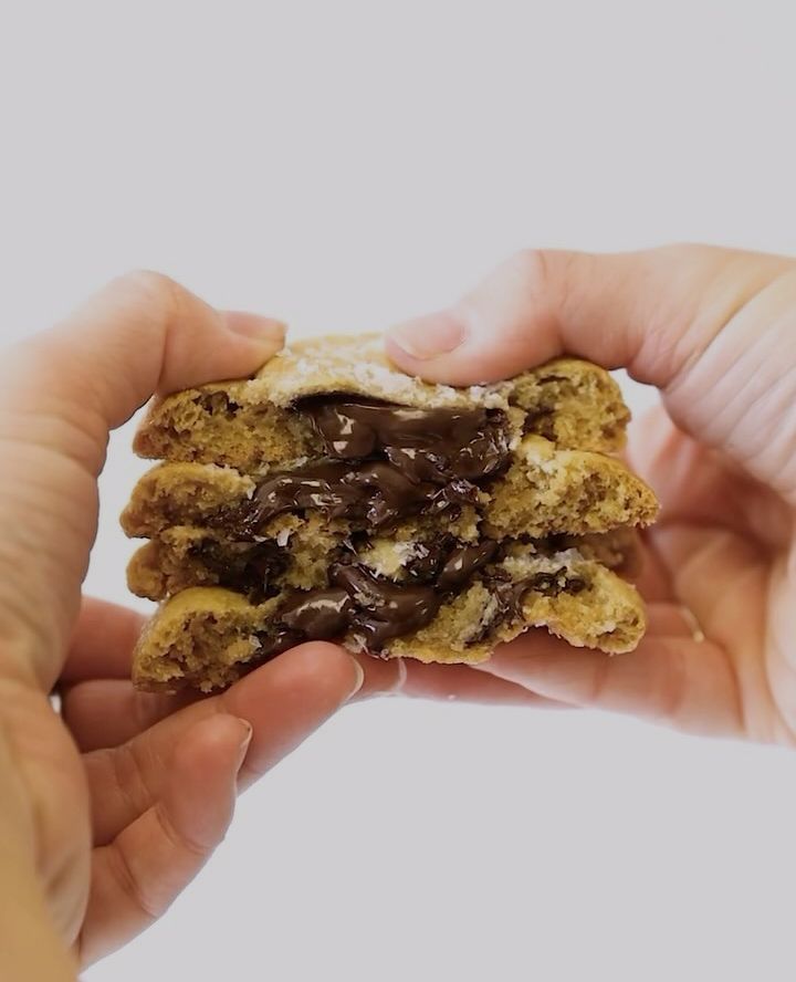 A person is holding a cookie with chocolate chips on it