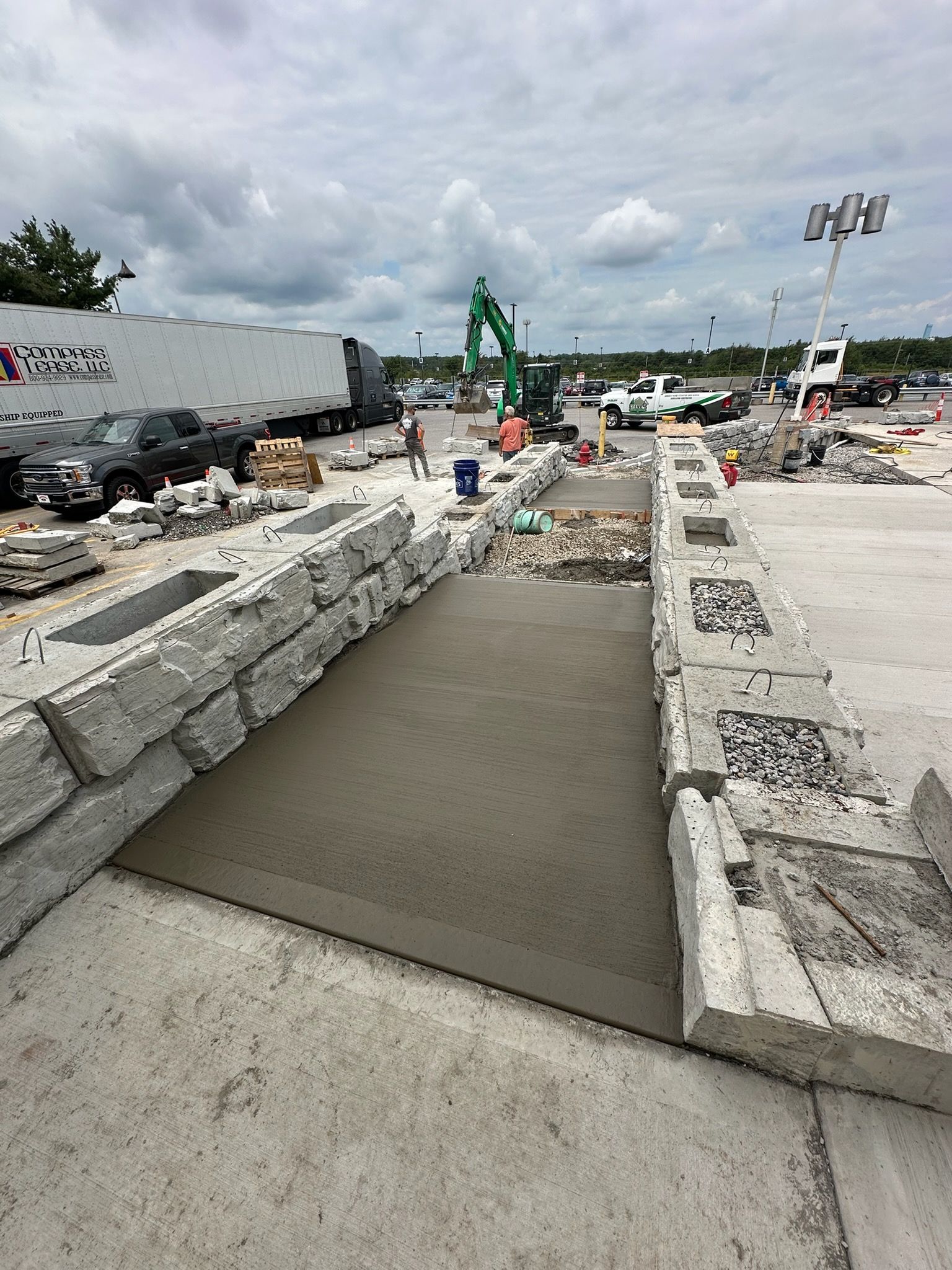 Concrete ramp at a construction site under cloudy sky, with equipment and debris around it