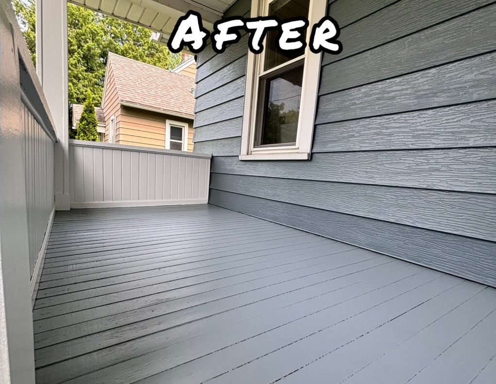 Front porch with weathered wood deck, white railing, and blue siding. - afte