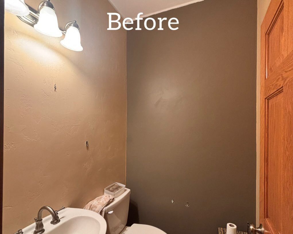 Small bathroom before remodel. Tan and dark gray walls, a wooden door, a toilet, and a sink. - before