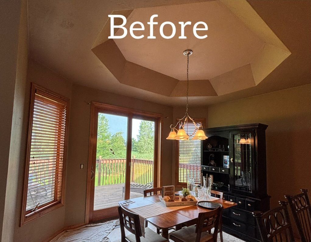 Dining room with a wood table, a black hutch, a chandelier, and an octagonal ceiling feature. - before
