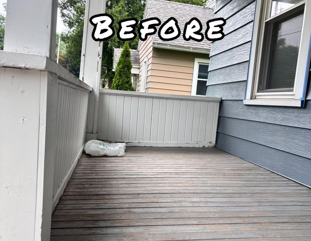 Front porch with weathered wood deck, white railing, and blue siding. - before