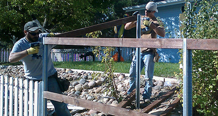 Two workers fixing the wooden fence