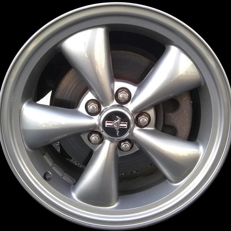 A close up of a silver wheel with a mustang logo on it