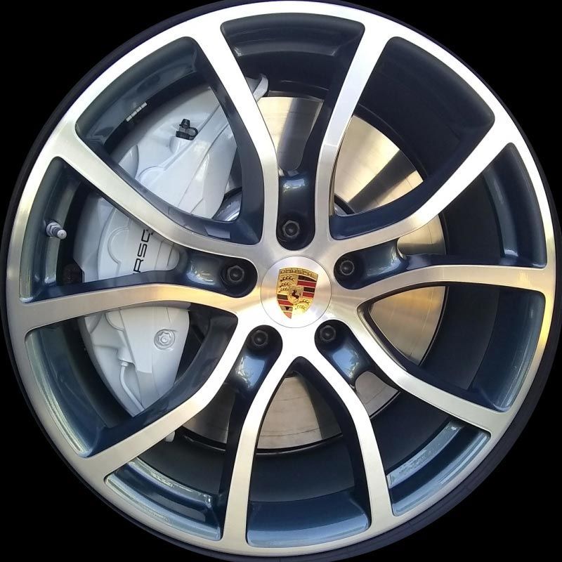 A close up of a porsche wheel with a white brake
