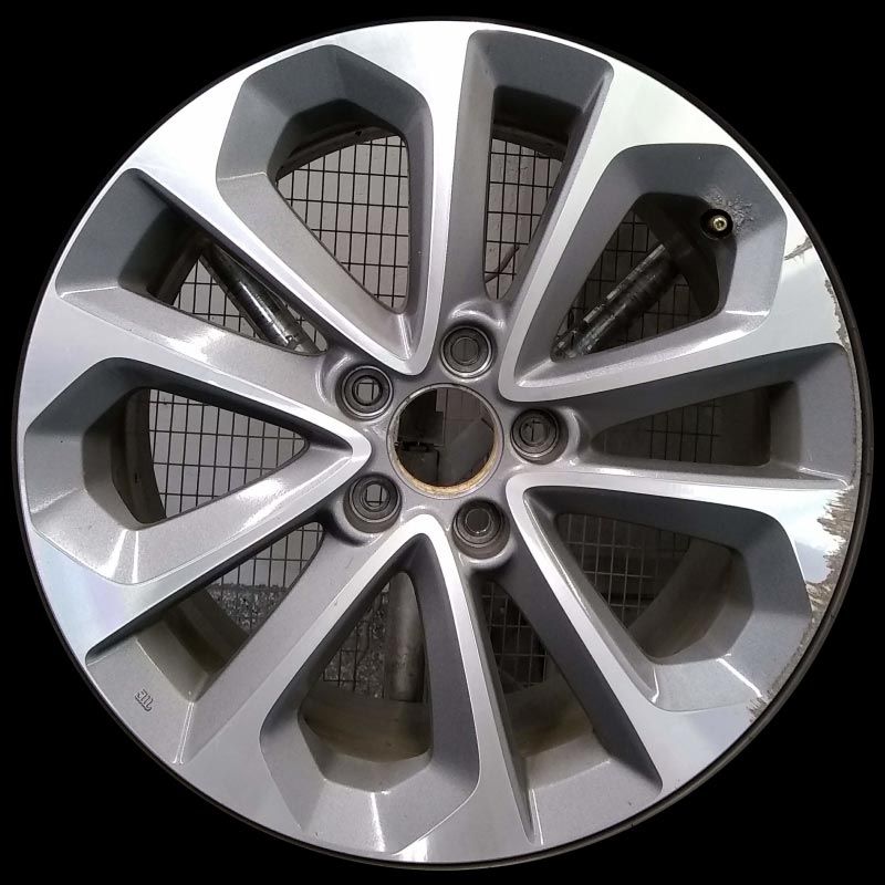 A close up of a silver car wheel on a black background