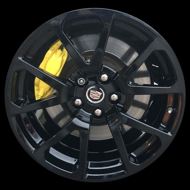 A black cadillac wheel with a yellow brake caliper