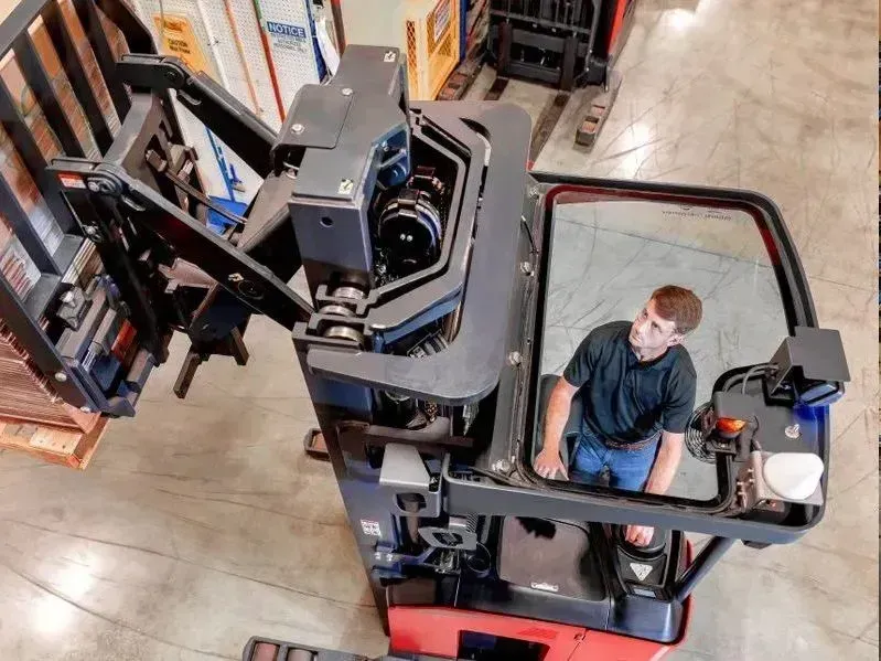 Worker operating a forklift in a warehouse aisle, viewed from above.