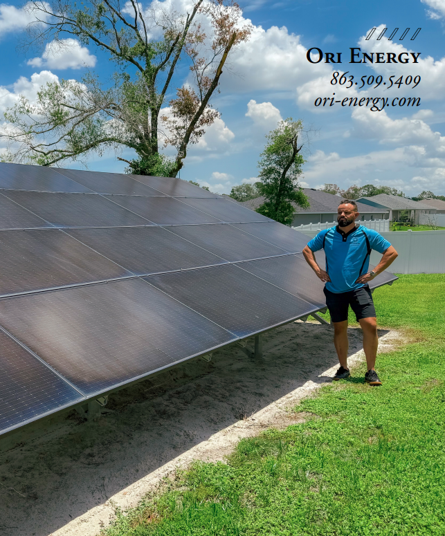 A man is standing in front of a large solar panel.