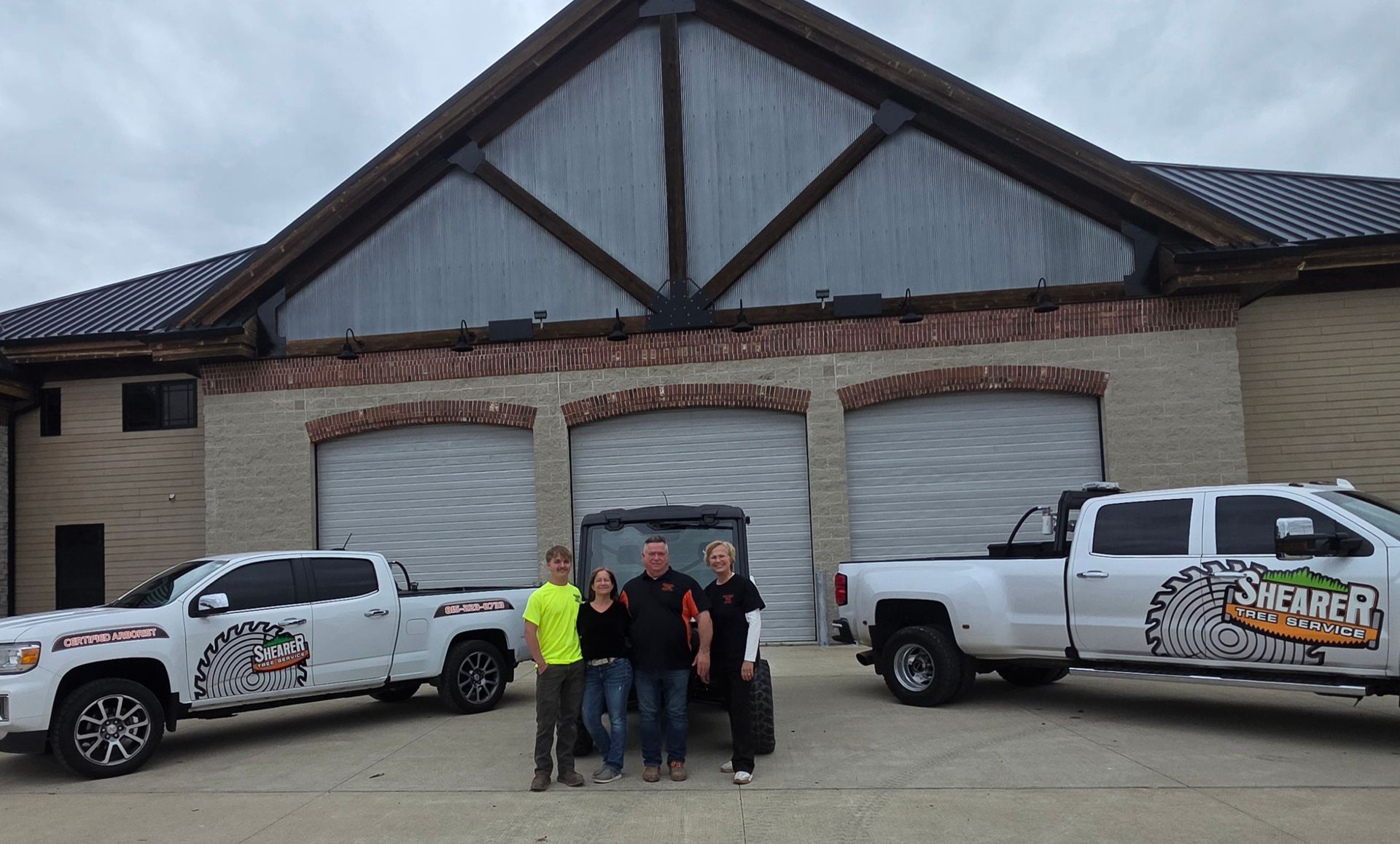 Group of people standing in front of a building with two white pickup trucks parked on either side