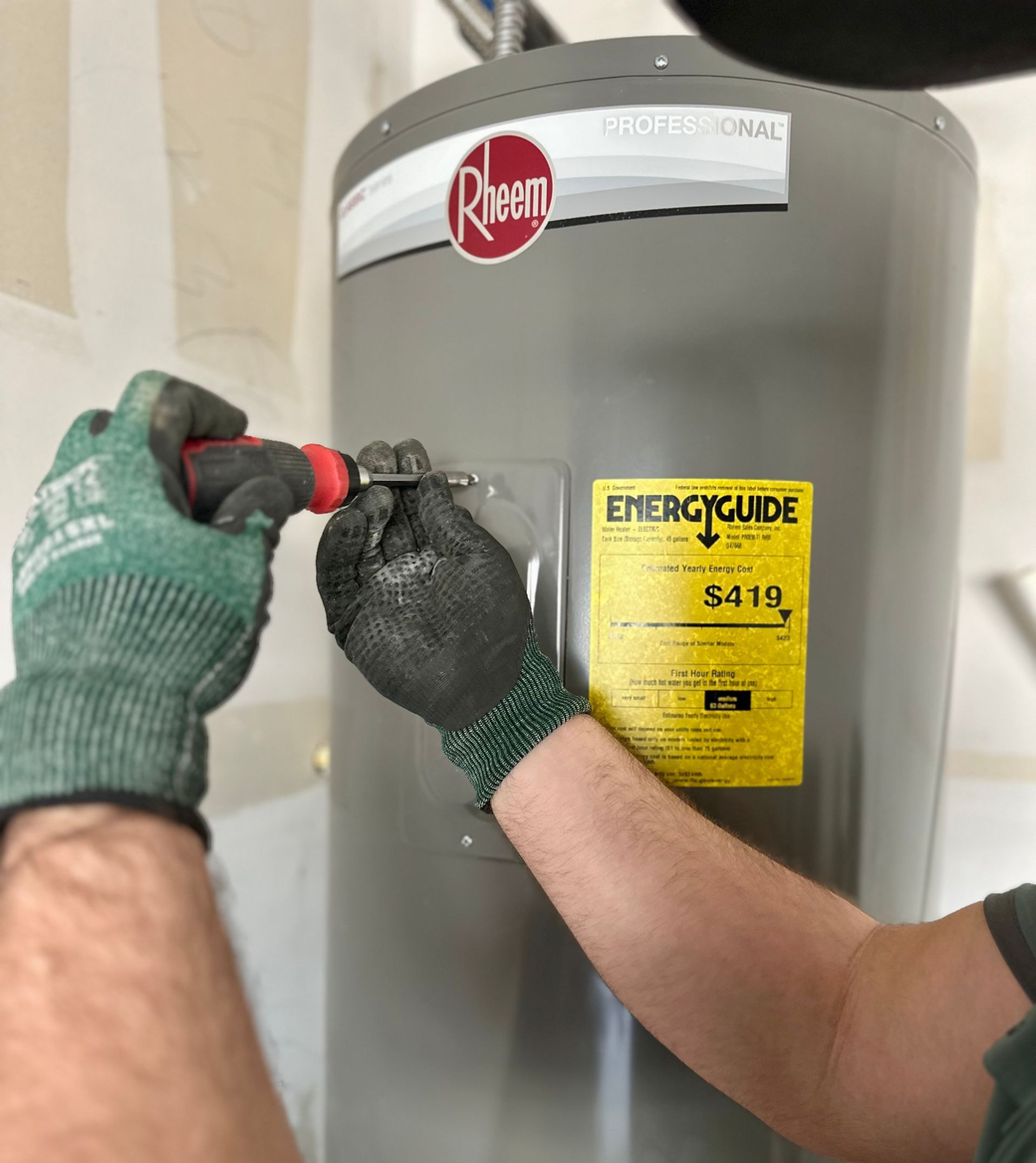 Person wearing gloves screws on a water heater, with an Energy Guide sticker visible.