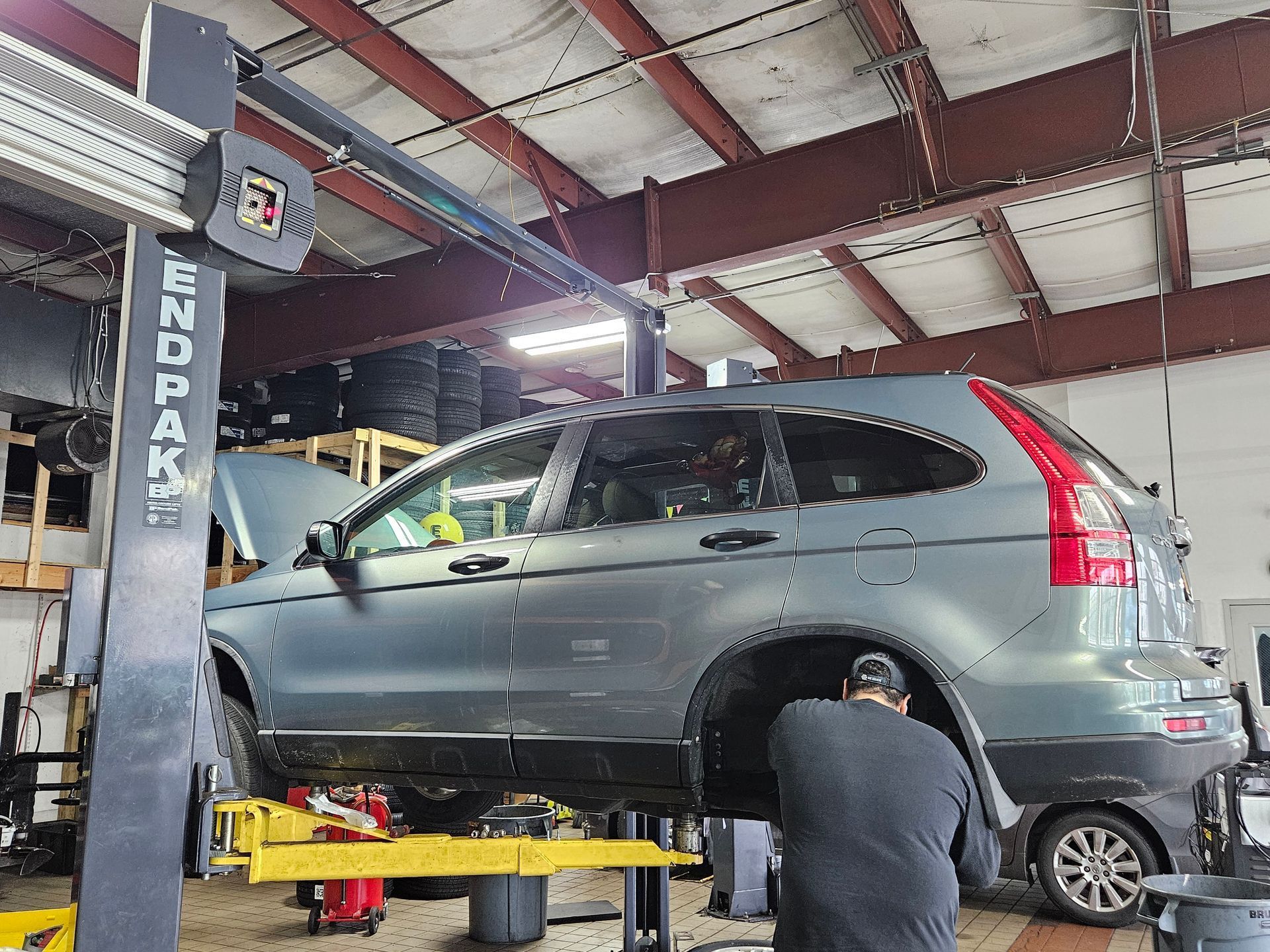 A man is working on a car on a lift in a garage.