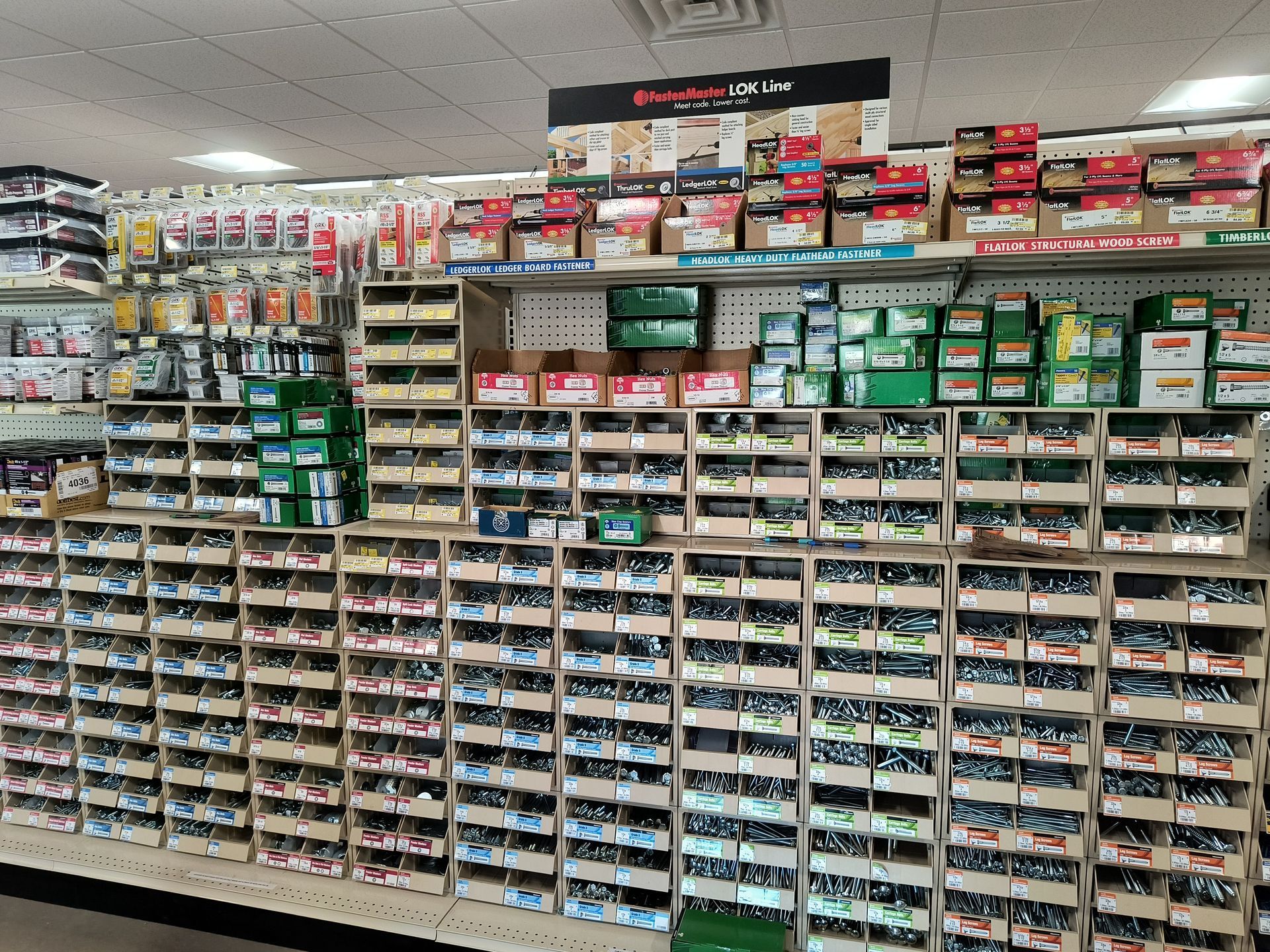 Shelves stocked with hardware, including screws, nails, and other fasteners in a retail setting.