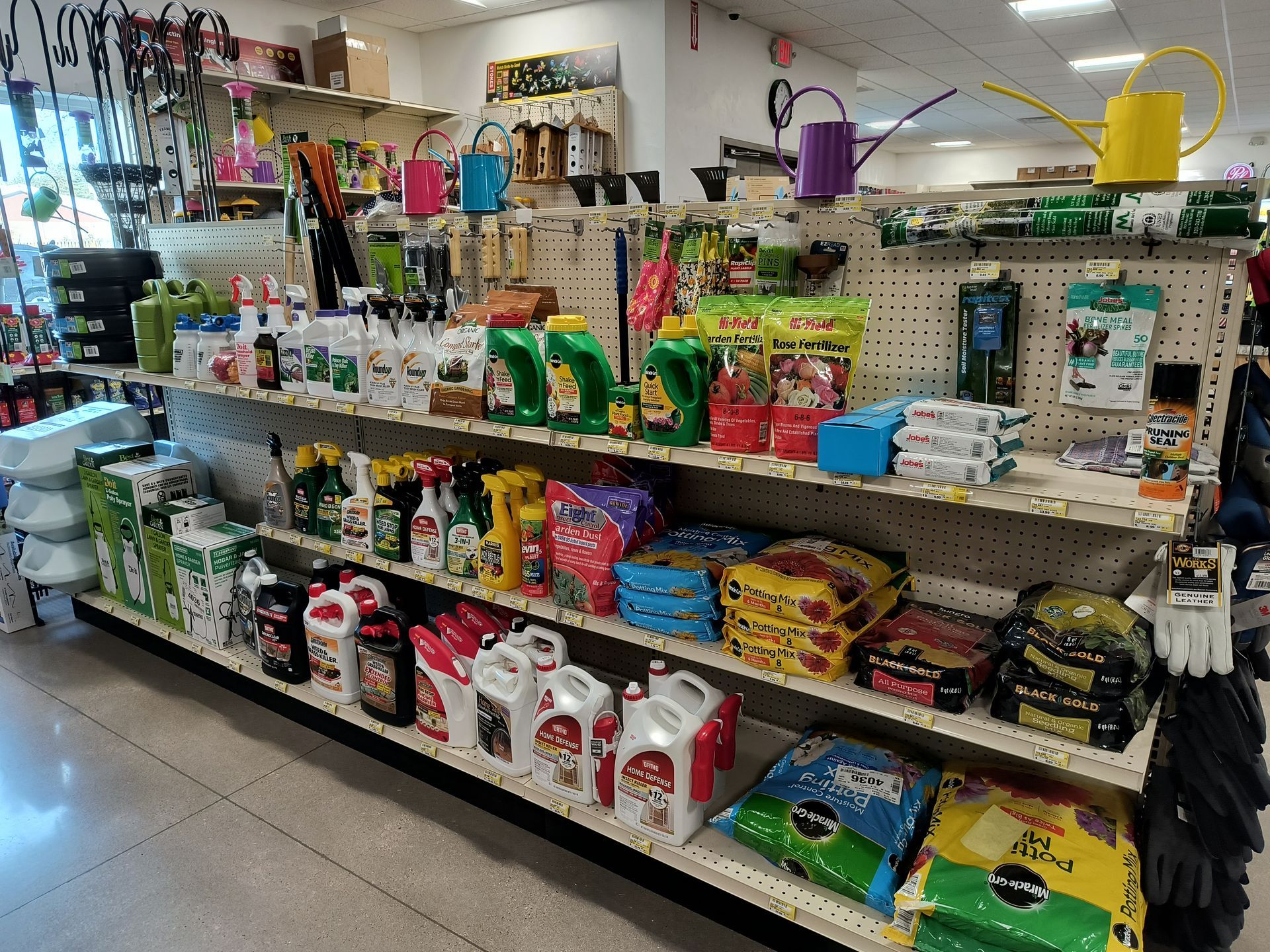 Shelves in a store filled with gardening supplies, including fertilizers, tools, and watering cans.