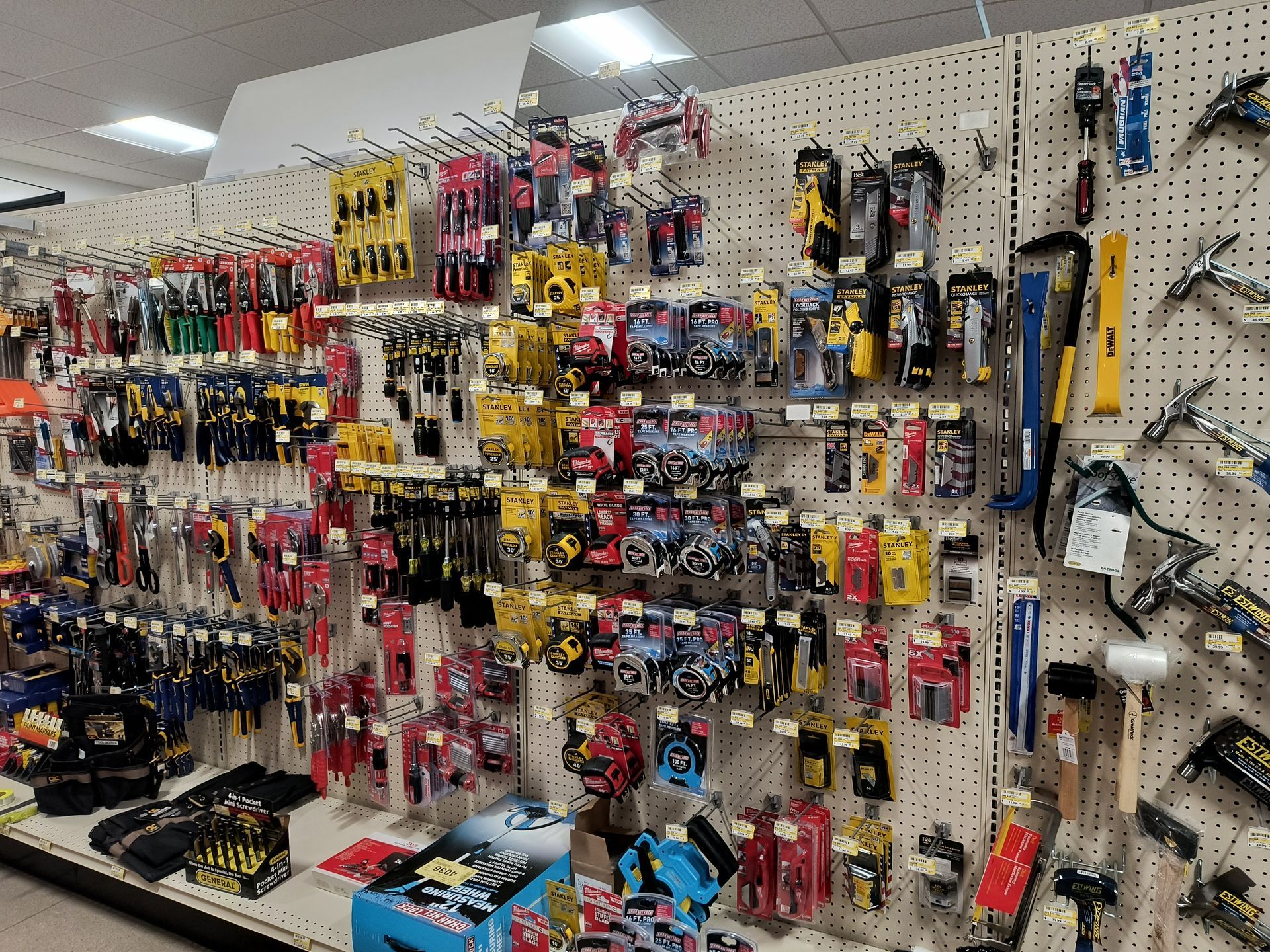 Tools and accessories displayed on a pegboard wall in a hardware store. Many tools are visible.