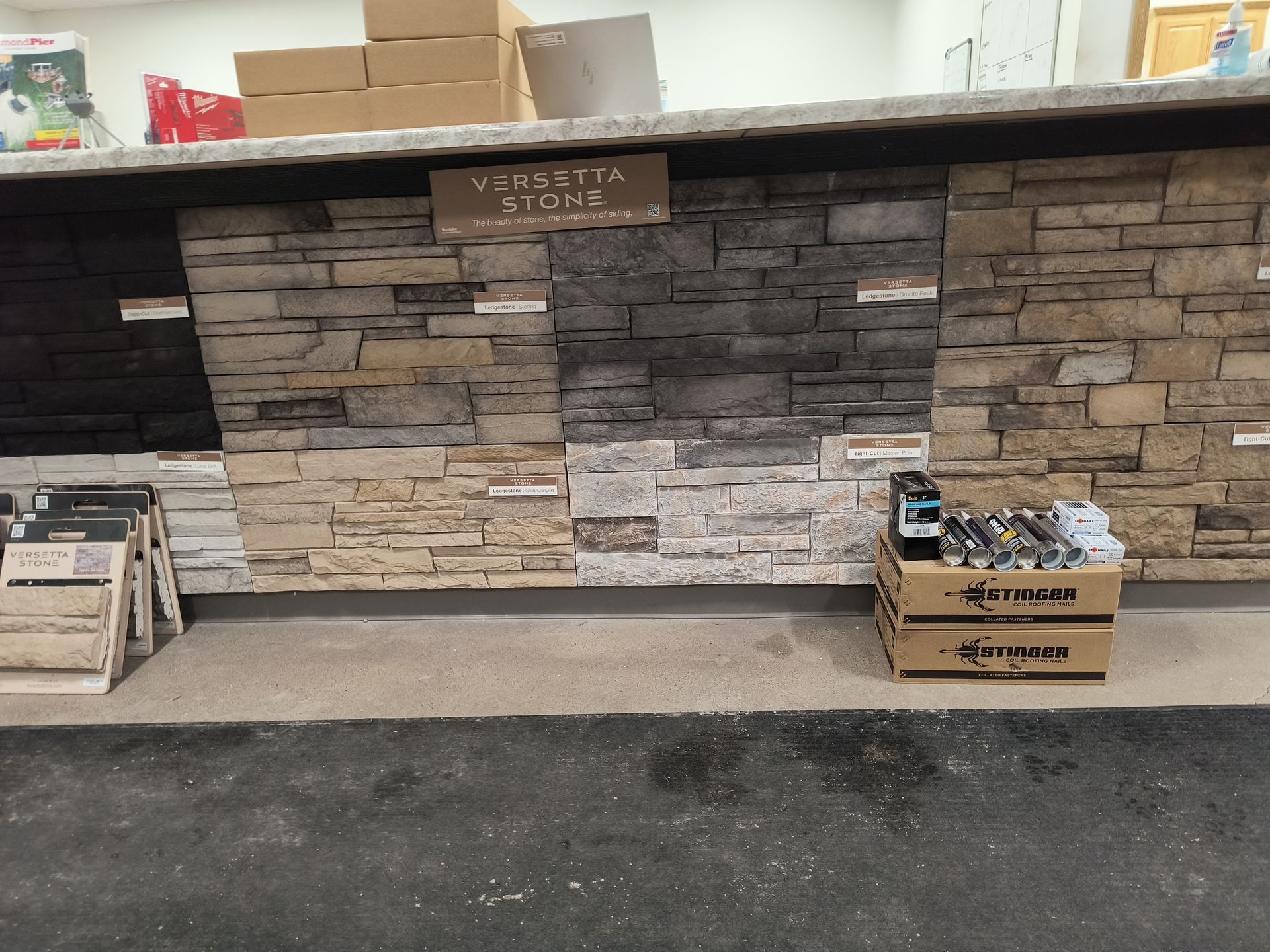 Stone veneer samples displayed at a store. Various colors and textures, with a box of tools in front.