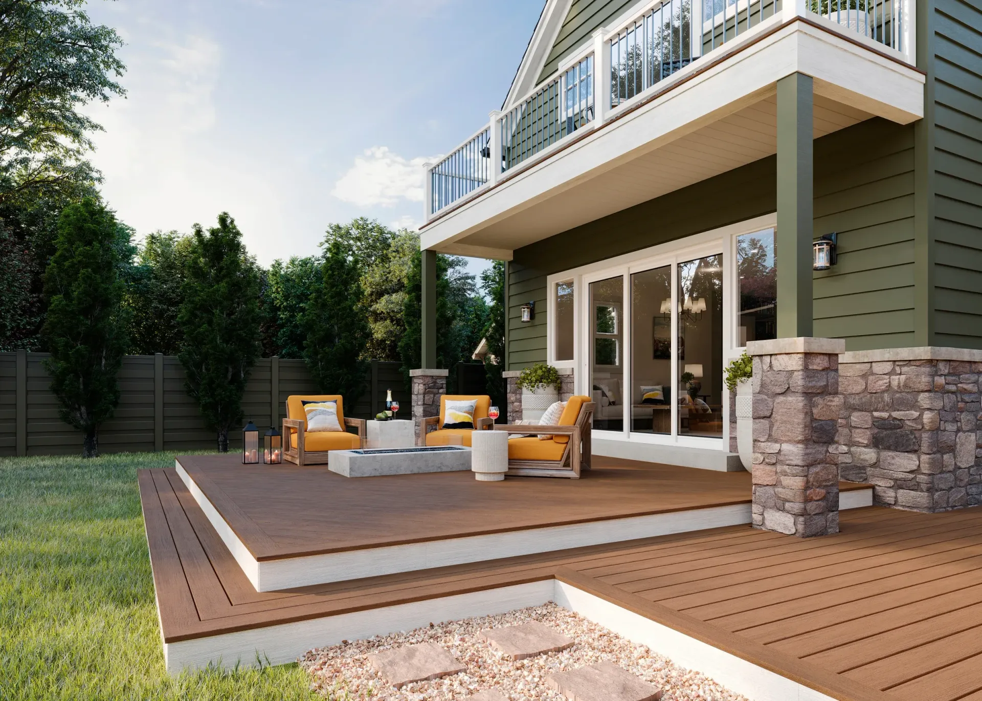 A backyard deck with two yellow armchairs, a fire pit, and a stone-accented home with a balcony.
