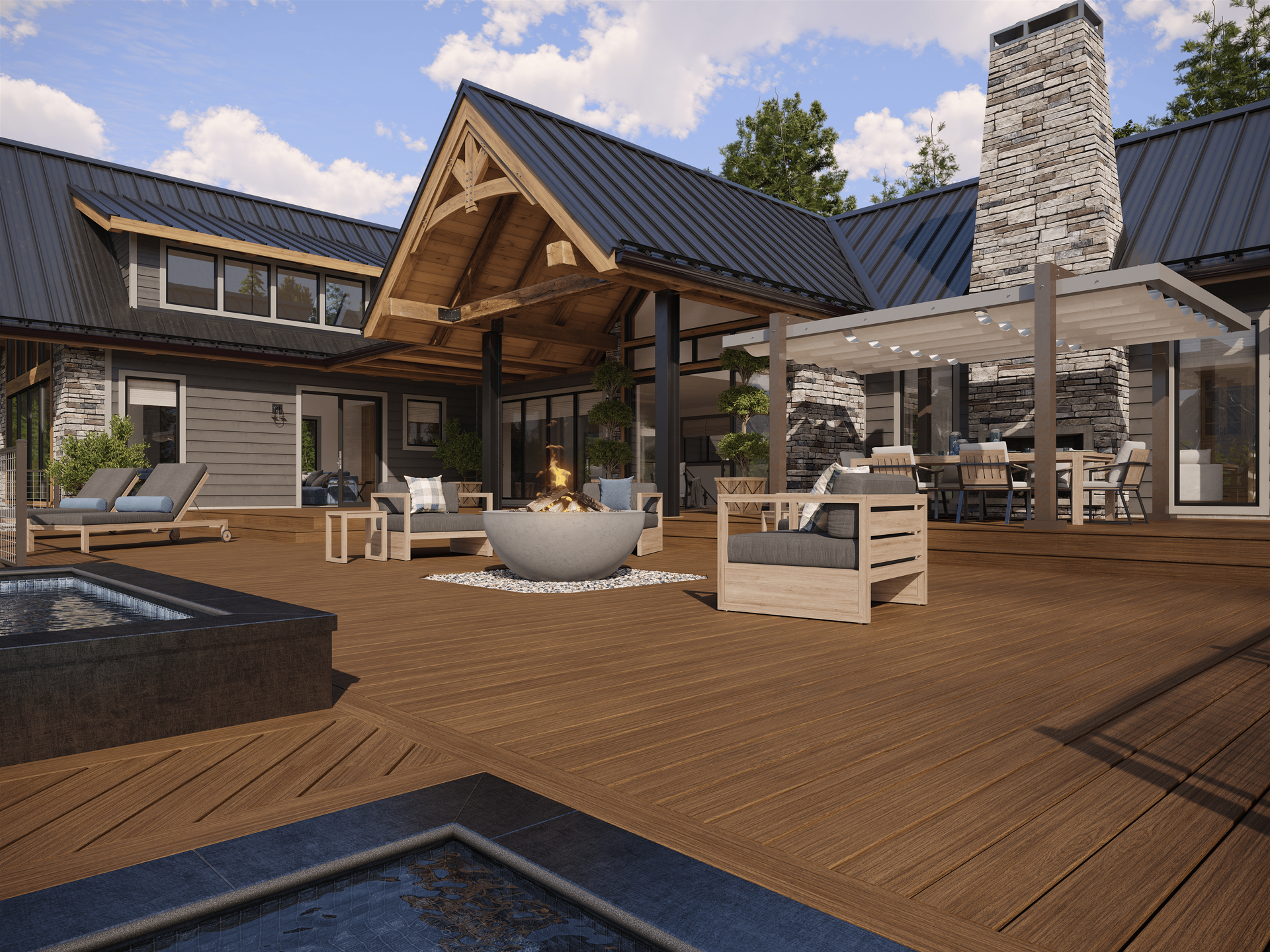 A spacious outdoor wood deck with lounge chairs, a fire pit, dining area, and a rustic home with a stone chimney.