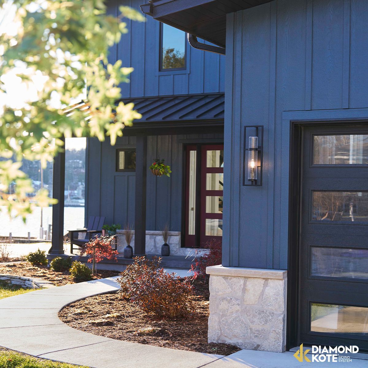 Modern blue house exterior with curved walkway, front entry, and landscaped shrubs