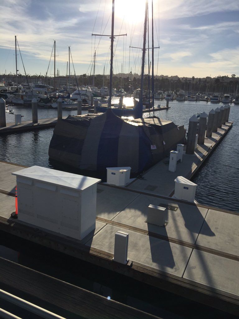 A row of boats are docked at a marina on a sunny day