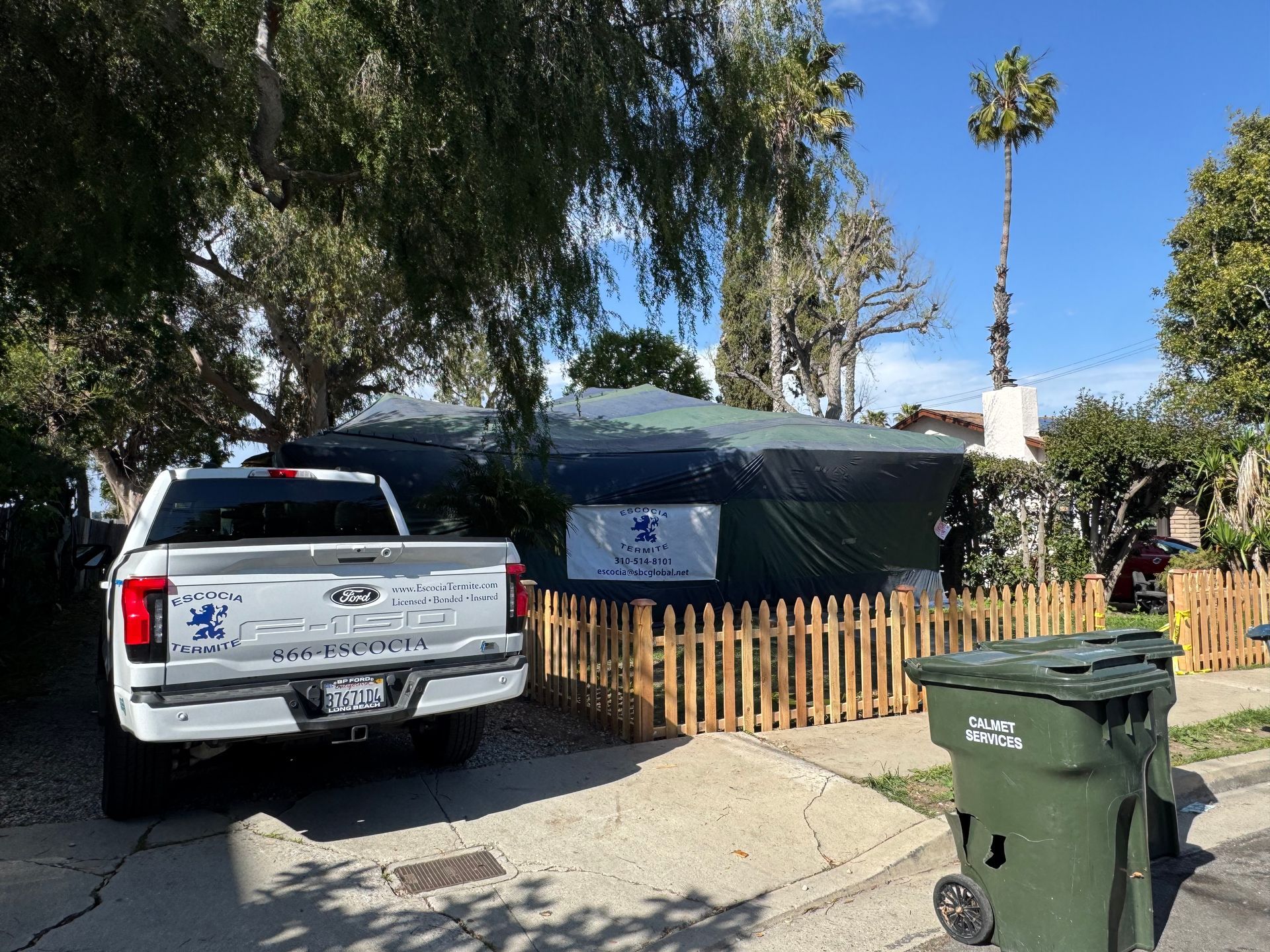 A white truck is parked in front of a tent in a yard.