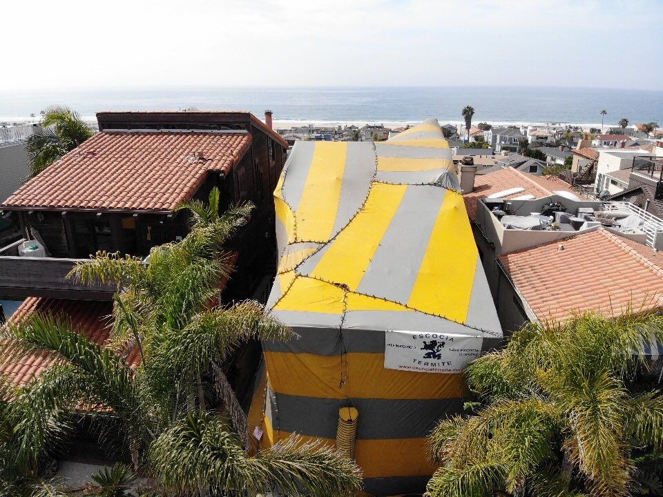 An aerial view of a house with a yellow and gray tarp on the roof