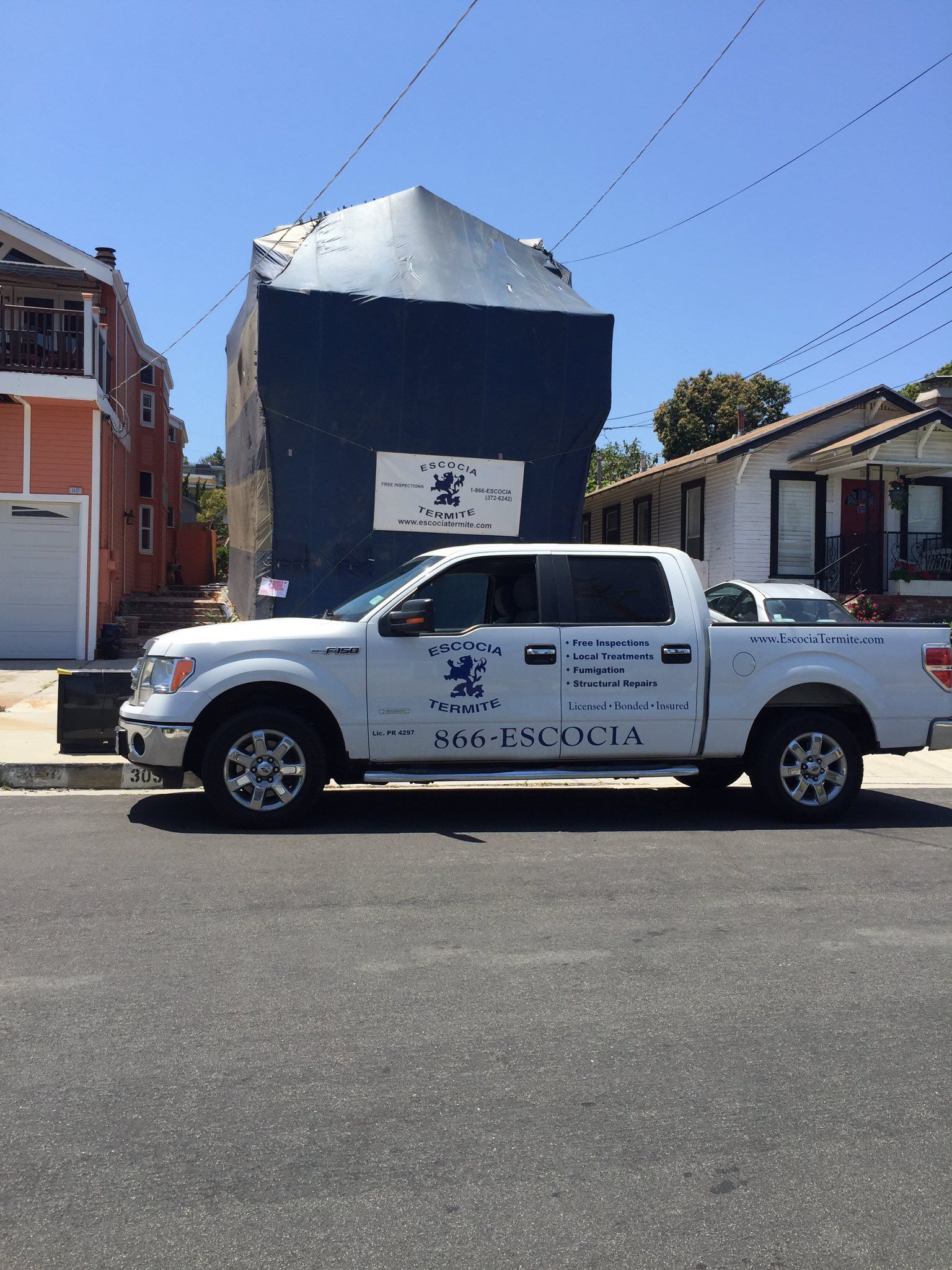 A white truck is parked on the side of the road in front of a building.
