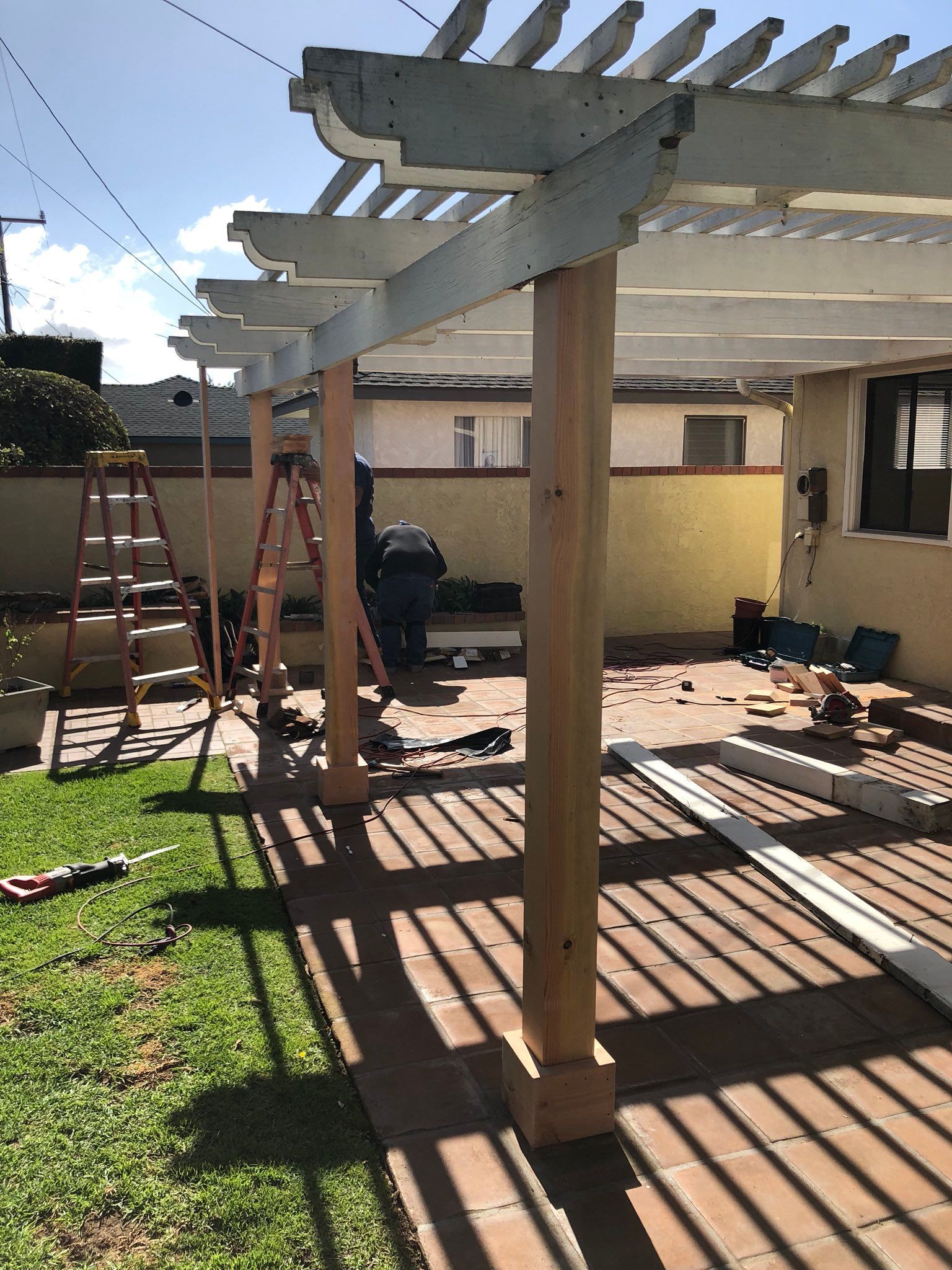 A pergola is being built in the backyard of a house.