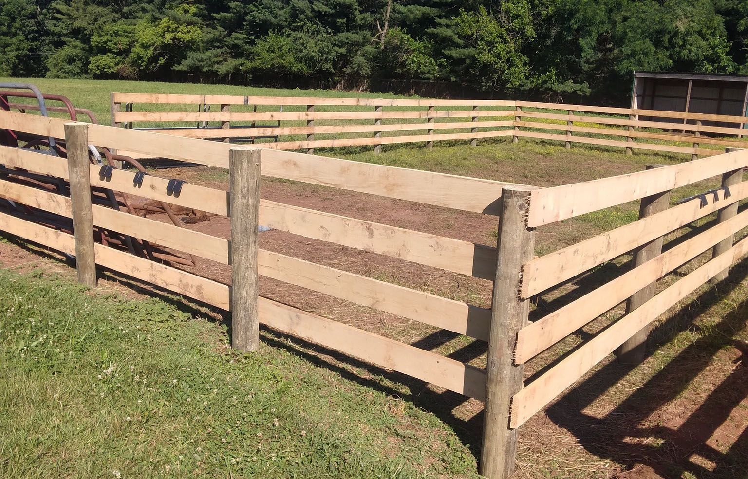 A wooden fence surrounds a grassy area in a field.