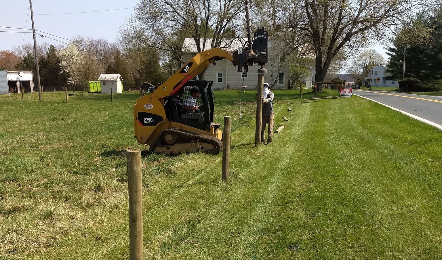 A bulldozer is working on a fence in a grassy field