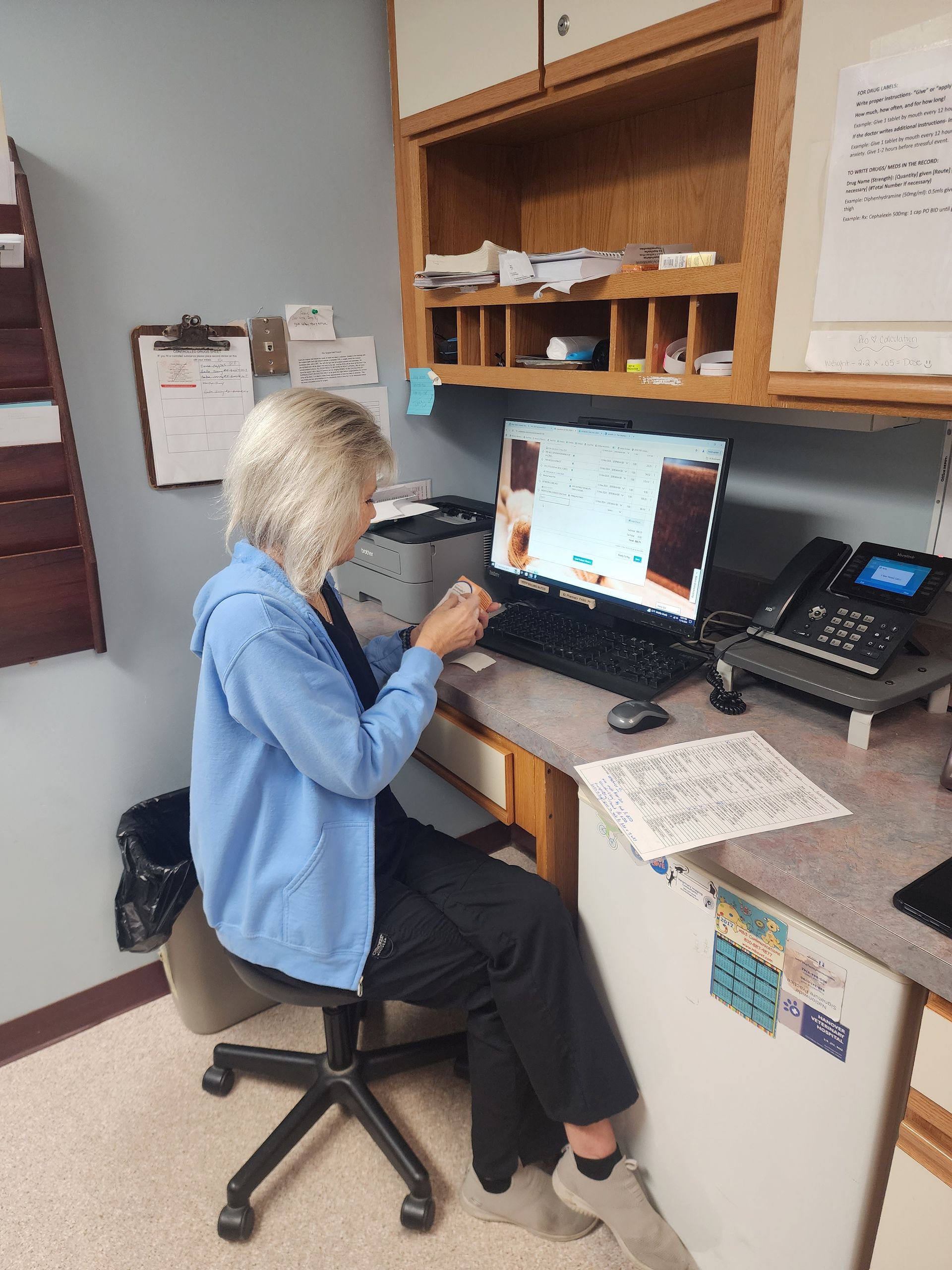 A woman is sitting at a desk in front of a computer.