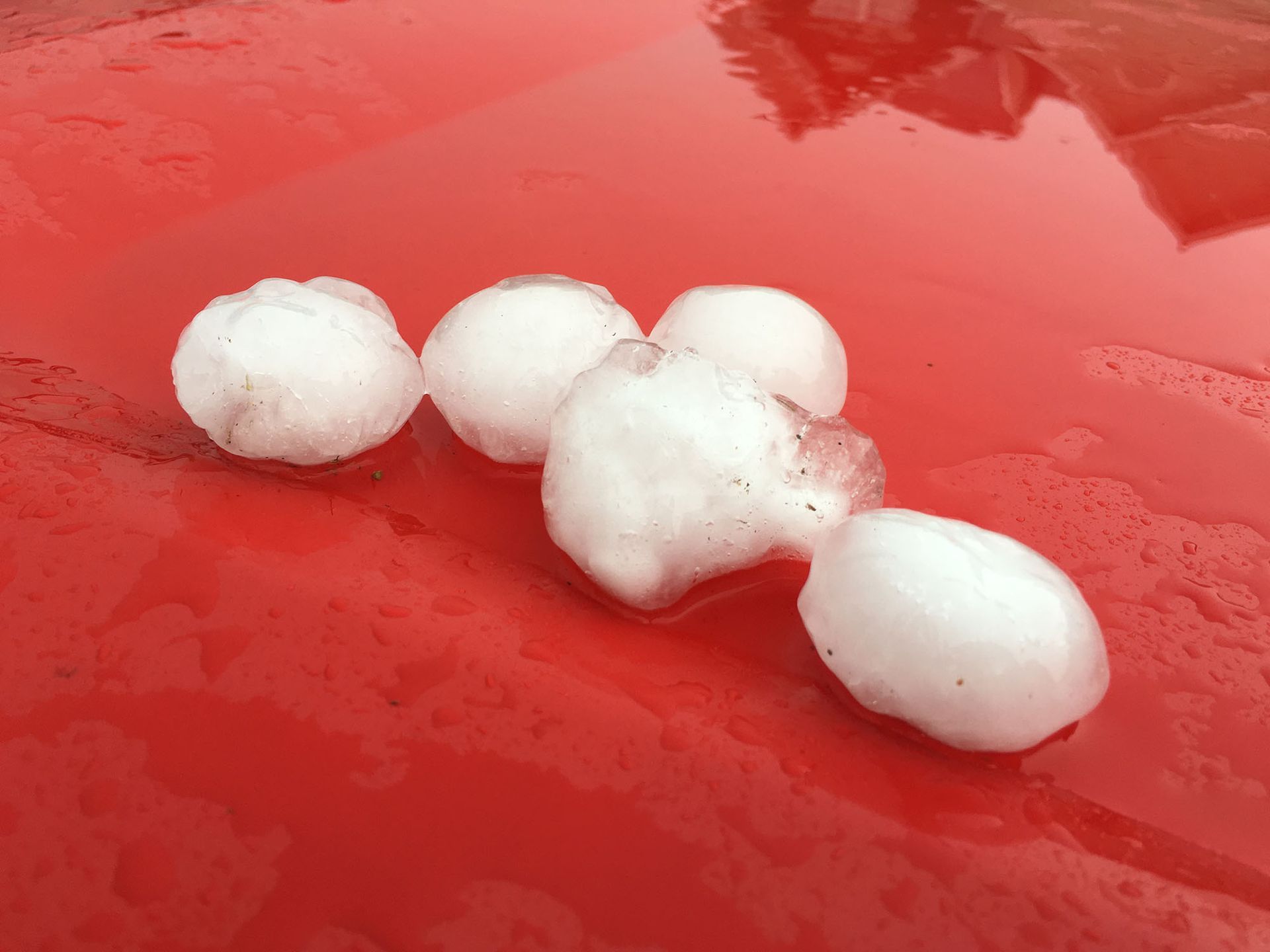 A bunch of hail balls are sitting on top of a red surface.