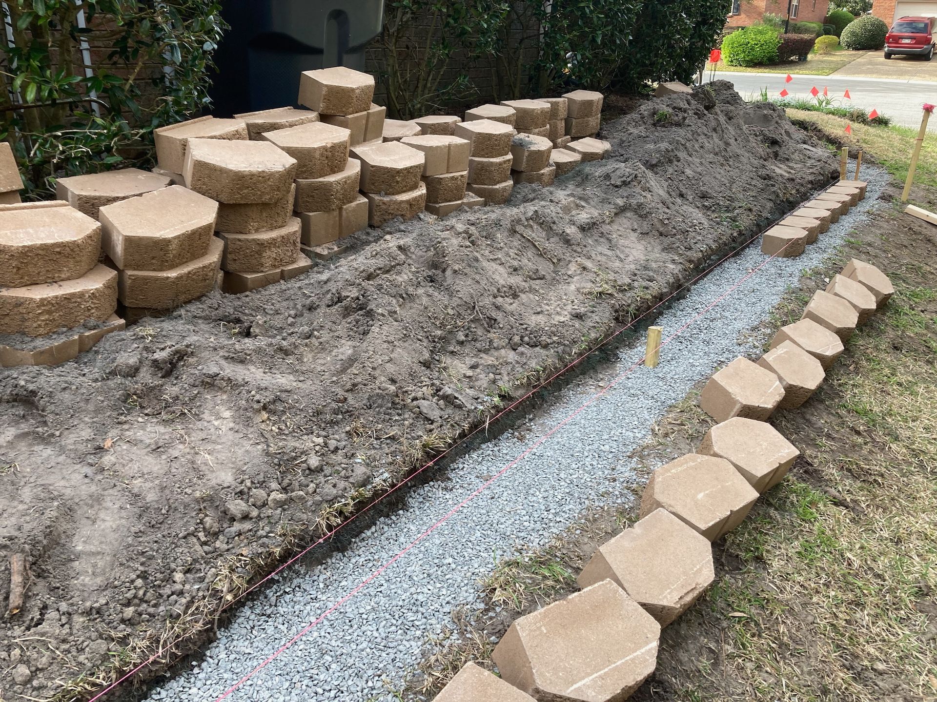 Construction of a garden bed with retaining wall blocks. A trench is filled with gravel and lined with blocks.