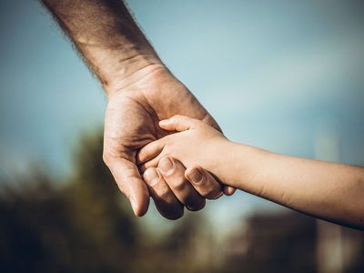 A man is holding a child's hand