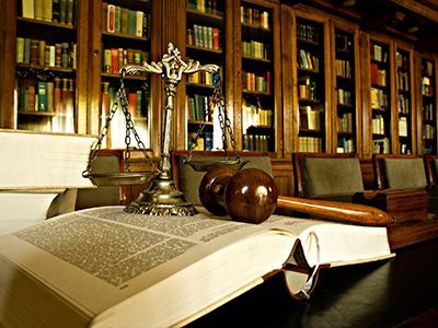 A scale of justice is sitting on top of an open book in a library