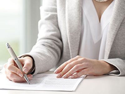 A man is writing on a piece of paper with a pen