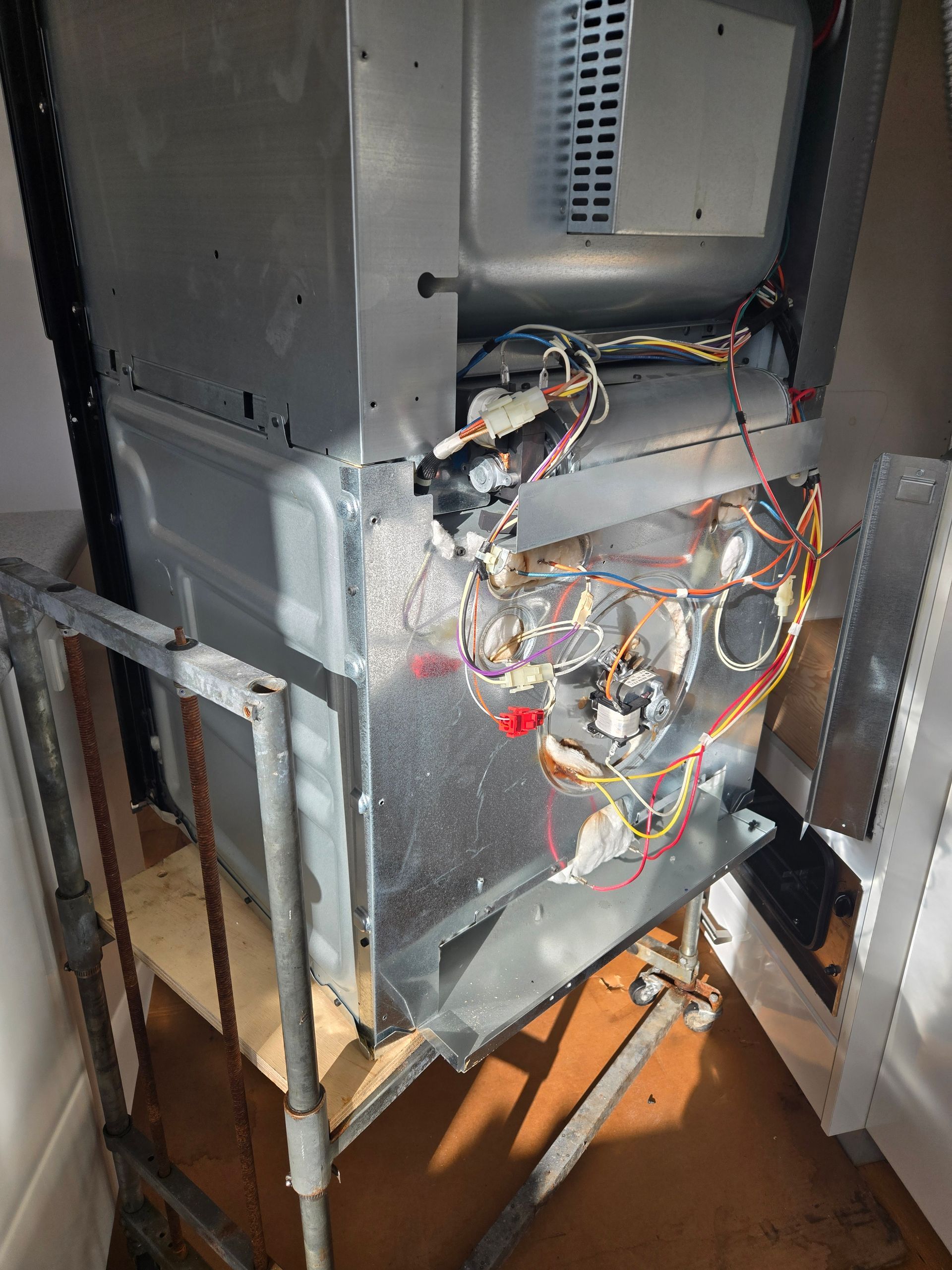 Open furnace or HVAC unit with exposed wiring and metal panels in a utility closet
