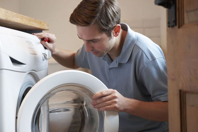 Person loading laundry into a front-loading washing machine in a laundry room